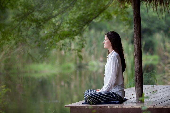 Femme médite au bord d'une rivière